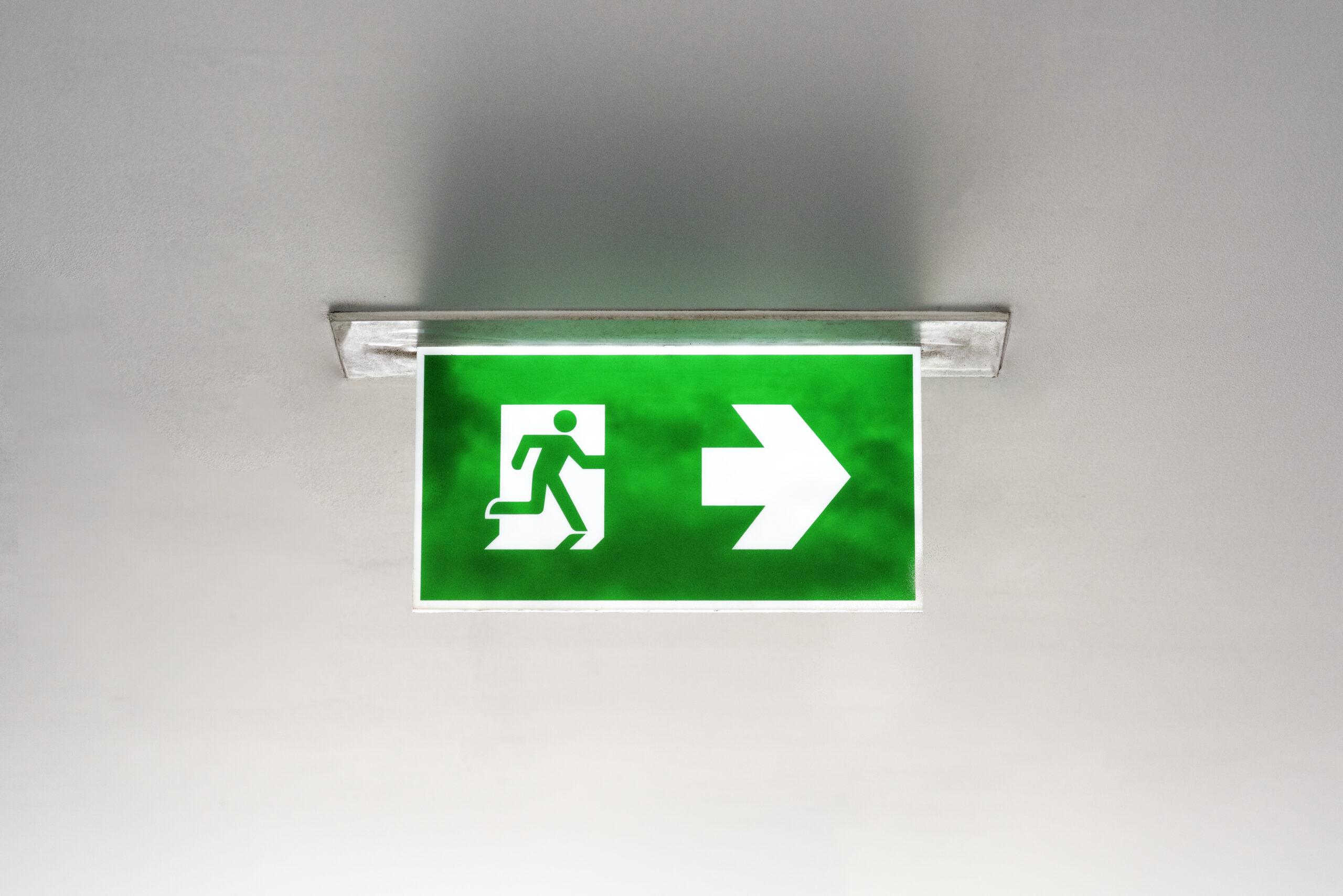 A green emergency exit sign with an arrow pointing right is mounted on the ceiling.