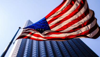 American flag waving in front of a tall building.