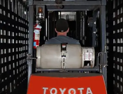 Rear view of a man operating a forklift in a narrow space.